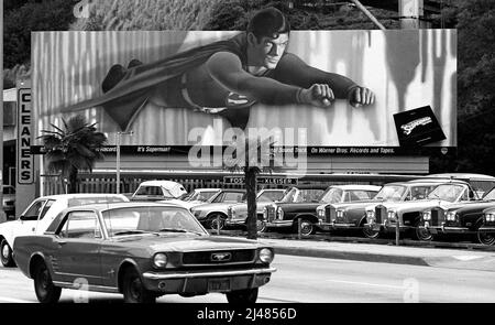 Christopher Reeve comme Superman strie à travers la bande de coucher du soleil à partir d'un grand panneau d'affichage peint à la main pour promouvoir le film à Los Angeles, CA en 1978 Banque D'Images