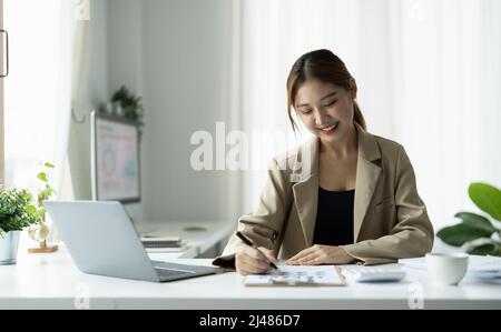 Femme d'affaires asiatique utilisant un ordinateur portable pour faire des finances mathématiques sur un bureau en bois dans le bureau, la taxe, la comptabilité, le concept financier Banque D'Images