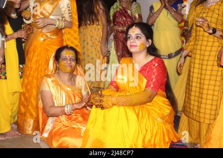 Mariée hindoue indienne avec pâte curcuma appliquée sur son visage en s'amusant avec sa famille et ses amis. Concept de mariage indien Banque D'Images