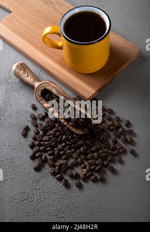 Tasse de café jaune avec grains de café sur fond de béton Banque D'Images