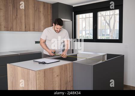 Un jeune homme argentin utilise du ruban de mesure avant de placer les comptoirs sur la cuisine. Banque D'Images