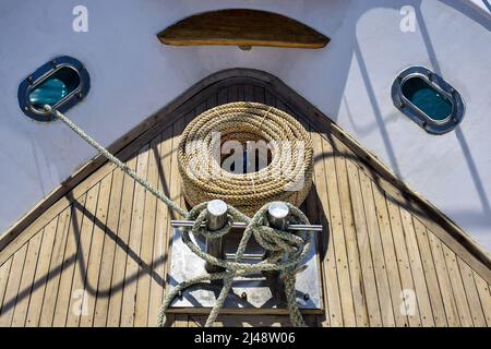 Arc de yacht blanc. Baie avec une corde épaisse se trouve sur une terrasse en bois. La corde est enroulée sur le montant d'ancrage. Vue de dessus. Gros plan. Mise au point sélective. Banque D'Images