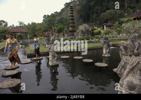 Les femmes se promonaient sur les traces de pierre au palais aquatique Tirta Gangga à Karangasem, Bali. Construit sur la base d'une croyance que l'eau est sainte, le Gangga de Tirta (tirta signifie « l'eau sainte »; Gangga fait référence au Gange en Inde) était un ancien palais royal du royaume de Karangasem. Banque D'Images