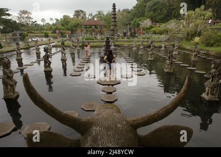 Les visiteurs marchent sur des traces de pierre au palais aquatique Tirta Gangga à Karangasem, Bali. Construit sur la base d'une croyance que l'eau est sainte, le Gangga de Tirta (tirta signifie « l'eau sainte »; Gangga fait référence au Gange en Inde) était un ancien palais royal du royaume de Karangasem. Banque D'Images