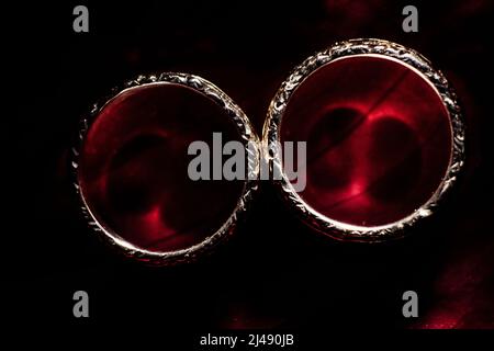 De jolies bagues dorées de mariage sur fond rouge foncé. Concept de mariage photo de haute qualité Banque D'Images