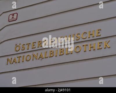 Vue sur le lettrage doré sur un mur peint en blanc à l'entrée de la Bibliothèque nationale autrichienne dans le centre historique de Vienne, Autriche. Banque D'Images