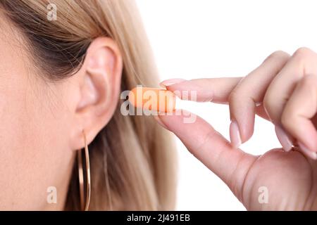 Gros plan de la femme insère des bouchons d'oreille orange dans les oreilles, sélection de bouchons d'oreille en silicone. Femme utilisant une protection contre le bruit dans un endroit bruyant ou dans l'eau. Non Banque D'Images