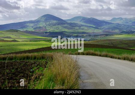 paysage sicilien avec route en campagne et ciel avec nuages gris Banque D'Images