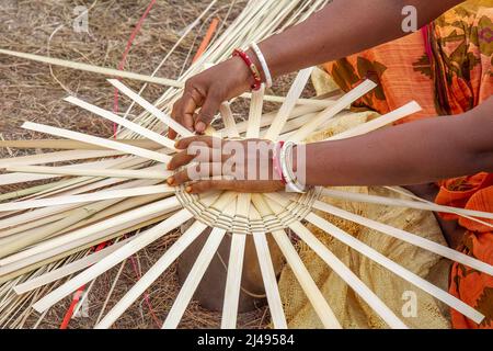 Les mains d'une femme indienne qui travaille en gros plan en train de tisser un panier avec des pailles en bambou Banque D'Images