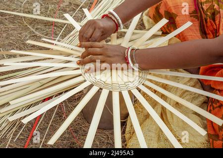 Les mains d'une femme indienne qui travaille en gros plan en train de tisser un panier avec des pailles en bambou Banque D'Images