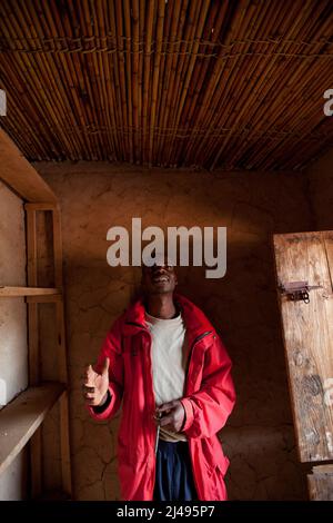 Thacien Kalinda, 24 ans, n à l'extérieur de ses boutiques dans le village. Sa famille s'est enfui au Congo en 1994 quand il avait 7 ans. Il était séparé de ses parents et de sept frères et sœurs qu'il n'a jamais vus depuis. Il était avec une tante qui l'a ramené à la maison 1996. Elle est morte lorsqu'il avait 18 ans au primaire en 6 et qu'il a abandonné l'école parce qu'il ne pouvait pas payer les frais d'école. Il a vécu comme un garçon de rue jusqu'à ce qu'il s'implique dans le programme. Grâce à ce projet, il a pu exploiter les terres dont il avait hérité de son père, rembourser 300 000 francs pour les biens pillés par son parent Banque D'Images