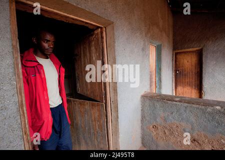 Thacien Kalinda, 24 ans, n à l'extérieur de ses boutiques dans le village. Sa famille s'est enfui au Congo en 1994 quand il avait 7 ans. Il était séparé de ses parents et de sept frères et sœurs qu'il n'a jamais vus depuis. Il était avec une tante qui l'a ramené à la maison 1996. Elle est morte lorsqu'il avait 18 ans au primaire en 6 et qu'il a abandonné l'école parce qu'il ne pouvait pas payer les frais d'école. Il a vécu comme un garçon de rue jusqu'à ce qu'il s'implique dans le programme. Grâce à ce projet, il a pu exploiter les terres dont il avait hérité de son père, rembourser 300 000 francs pour les biens pillés par son parent Banque D'Images