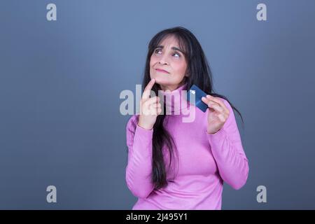 belle femme avec expression pensive et carte de crédit sur fond gris Banque D'Images