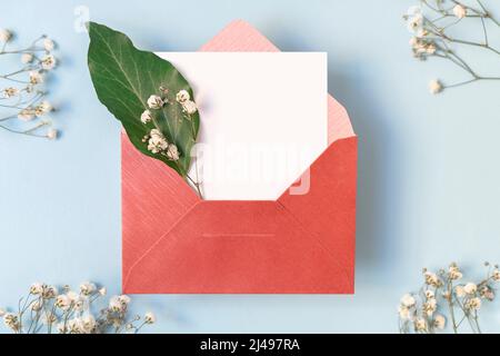 Composition florale avec enveloppe et carte blanche vierge et fleurs blanches, vue de dessus, maquette Banque D'Images