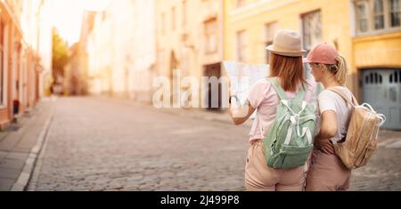 Deux femmes à la recherche de l'emplacement des sites touristiques sur la carte de la vieille Tallinn, Estonie. Banque D'Images