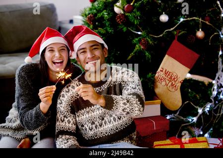 Noël est le jour qui tient tout le temps ensemble. Photo d'un jeune couple assis près de son arbre de Noël. Banque D'Images