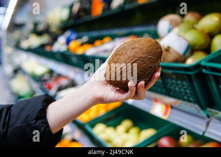 Femme client choisissant la noix de coco mûre au supermarché. Gros plan. Banque D'Images