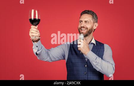 Happy man toastmaster lève un verre de vin pour proposer des toasts avant de boire un fond rouge, des encouragements Banque D'Images