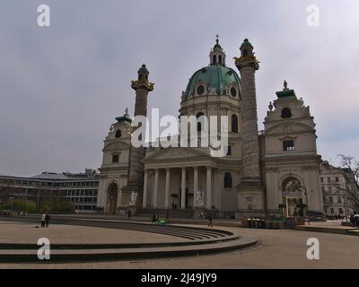 Vue sur la célèbre église Karlskirche située sur la place Karlsplatz dans le centre historique de Vienne, Autriche, par une journée nuageux au printemps avec des gens relaxants. Banque D'Images