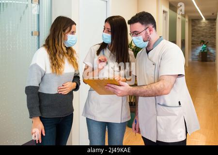Deux médecins tiennent le presse-papiers tout en parlant au patient au centre de santé Banque D'Images