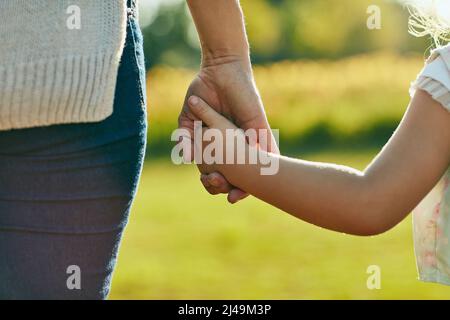 Gardez-les à proximité, en toute sécurité. Photo courte d'une petite fille tenant une main de womans méconnaissable dans le parc. Banque D'Images