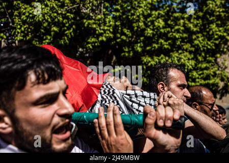 Kafr Laqif, Territoires palestiniens. 13th avril 2022. Des parents palestiniens portent le corps de Mohamed Assaf, qui a été tué par balle plus tôt dans la journée par des soldats israéliens, lors de ses funérailles dans le village de Kafr Laqif en Cisjordanie. Selon le ministère de la Santé de Ramallah, cet homme de 34 ans a été frappé dans la poitrine lors d'affrontements avec des soldats israéliens à Naplouse. L'armée israélienne a déclaré qu'elle avait détenu 15 personnes au total, après avoir déclaré que des opérations anti-terroristes étaient en cours en Cisjordanie, y compris à Naplouse. Crédit : Ilia Yefimovich/dpa/Alay Live News Banque D'Images