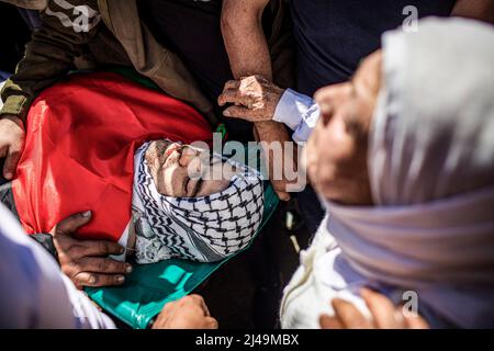 Kafr Laqif, Territoires palestiniens. 13th avril 2022. Des parents palestiniens portent le corps de Mohamed Assaf, qui a été tué par balle plus tôt dans la journée par des soldats israéliens, lors de ses funérailles dans le village de Kafr Laqif en Cisjordanie. Selon le ministère de la Santé de Ramallah, cet homme de 34 ans a été frappé dans la poitrine lors d'affrontements avec des soldats israéliens à Naplouse. L'armée israélienne a déclaré qu'elle avait détenu 15 personnes au total, après avoir déclaré que des opérations anti-terroristes étaient en cours en Cisjordanie, y compris à Naplouse. Crédit : Ilia Yefimovich/dpa/Alay Live News Banque D'Images