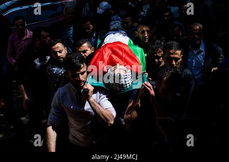 Kafr Laqif, Territoires palestiniens. 13th avril 2022. Des parents palestiniens portent le corps de Mohamed Assaf, qui a été tué par balle plus tôt dans la journée par des soldats israéliens, lors de ses funérailles dans le village de Kafr Laqif en Cisjordanie. Selon le ministère de la Santé de Ramallah, cet homme de 34 ans a été frappé dans la poitrine lors d'affrontements avec des soldats israéliens à Naplouse. L'armée israélienne a déclaré qu'elle avait détenu 15 personnes au total, après avoir déclaré que des opérations anti-terroristes étaient en cours en Cisjordanie, y compris à Naplouse. Crédit : Ilia Yefimovich/dpa/Alay Live News Banque D'Images