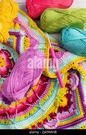 Pelins colorés de fil disposés à côté d'une couverture crochetée Banque D'Images