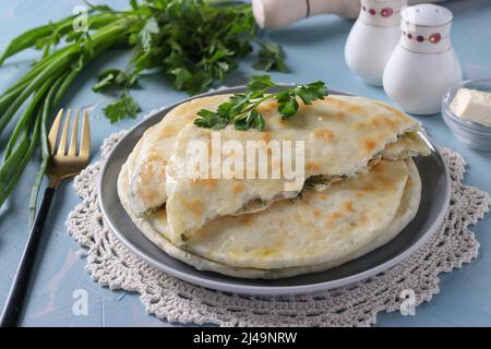 Ronds de gâteaux de khachapuri faits maison au fromage brynza, frits dans une poêle, fond bleu clair, gros plan Banque D'Images