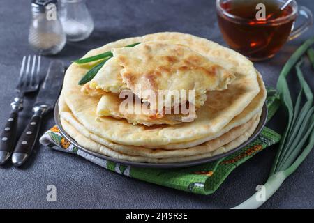 Autour des gâteaux khashapuri faits maison avec du fromage, frits dans la poêle, sur le petit déjeuner et une tasse de thé. Cuisine géorgienne traditionnelle Banque D'Images