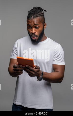 Un gars choqué regardant le gadget dans ses mains Banque D'Images