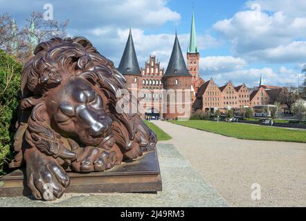 Sculpture de lion endormi en fer devant la porte de Holsten ou Holstentor, le point de repère de la ville hanséatique historique de Lubeck en Allemagne, bleu s. Banque D'Images