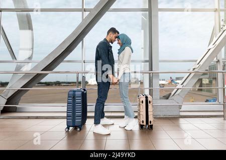 Portrait d'un couple islamique aimant qui colle à l'aéroport tout en attendant le vol Banque D'Images