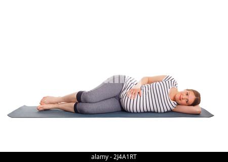 Femme enceinte faisant du yoga asana Parsva Savasana Banque D'Images