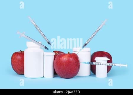 Fruits de pomme injectés avec des seringues à côté des flacons de pilules. Concept pour les aliments ou pesticides génétiquement modifiés Banque D'Images