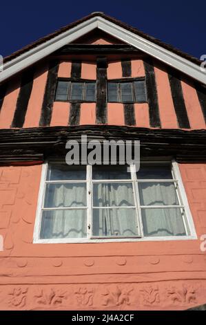 La dernière section d'un hall de 15th siècle situé au 13 High Street, Lavenham, Suffolk, Angleterre, présente des motifs fleuris-de-lis et des motifs géométriques de portcullis sous une poutre de bresSummer sculptée supportant un toit en bois encadré percé de deux fenêtres en chêne-mullioné. Banque D'Images