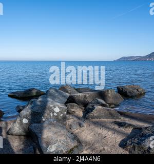 Blocs comme partie d'un brise-vague dans un lac. Photo du lac Vattern, Suède. Bleu de l'eau et du ciel en arrière-plan Banque D'Images