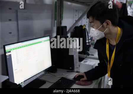 (220413) -- SHANGHAI, le 13 avril 2022 (Xinhua) -- le superviseur Wu Renhua vérifie les commandes en ligne tôt le matin à la division de sortie de Meituan Maicai dans l'est de la Chine Shanghai, le 12 avril 2022. Environ 1 400 commandes en ligne ont été passées en dix minutes à partir de 6 heures du matin mardi. Plus de 30 membres du personnel de la plate-forme d'épicerie en ligne Meituan Maicai, vivant et travaillant à la division de point de vente située sur la route Yixian de Shanghai, se sont occupés à préparer des fournitures pour les résidents. Ils sont engagés dans le tri et l'emballage des produits d'épicerie commandés avant que les articles soient livrés aux clients par co Banque D'Images