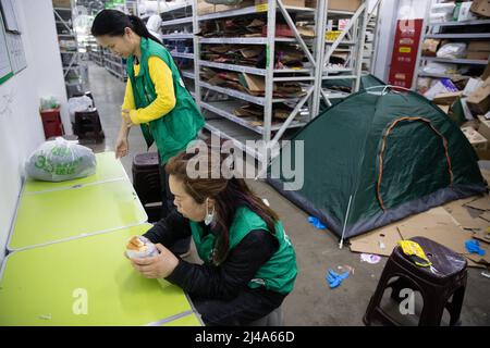 (220413) -- SHANGHAI, le 13 avril 2022 (Xinhua) -- les membres du personnel ont le petit déjeuner à la division de sortie de Meituan Maicai, dans l'est de la Chine, Shanghai, le 12 avril 2022. Plus de 30 membres du personnel de la plate-forme d'épicerie en ligne Meituan Maicai, vivant et travaillant à la division de point de vente située sur la route Yixian de Shanghai, se sont occupés à préparer des fournitures pour les résidents. Ils sont engagés dans le tri et l'emballage des produits d'épicerie commandés avant que les articles soient livrés aux clients par des coursiers. Au cours de la récente résurgence épidémique, en moyenne plus de 3 000 ordres sont traités par leur division o Banque D'Images