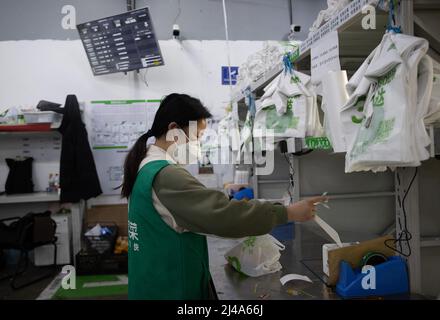 (220413) -- SHANGHAI, le 13 avril 2022 (Xinhua) -- Un membre du personnel trie et emboîte les produits d'épicerie commandés à la division de Meituan Maicai, dans l'est de la Chine, Shanghai, le 12 avril 2022. Plus de 30 membres du personnel de la plate-forme d'épicerie en ligne Meituan Maicai, vivant et travaillant à la division de point de vente située sur la route Yixian de Shanghai, se sont occupés à préparer des fournitures pour les résidents. Ils sont engagés dans le tri et l'emballage des produits d'épicerie commandés avant que les articles soient livrés aux clients par des coursiers. Au cours de la récente résurgence épidémique, une moyenne de plus de 3 000 ordres sont han Banque D'Images