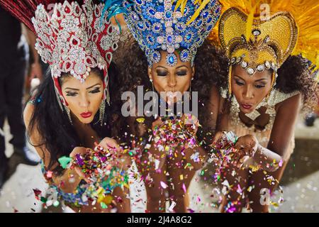 Diffuser leur magie dans la nuit. Prise de danseuses de samba soufflant des confettis de leurs mains tout en se présentant dans un carnaval. Banque D'Images