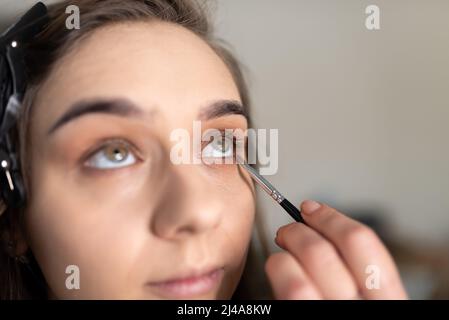 Maquilleuse application de l'ombre oculaire à la paupière inférieure d'une fille avec un pinceau. Photo de haute qualité Banque D'Images