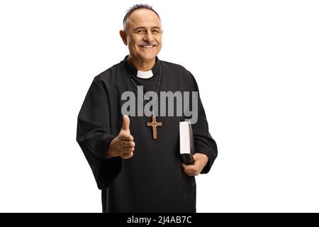 Heureux prêtre gesturant poignée de main et tenant une bible isolée sur fond blanc Banque D'Images