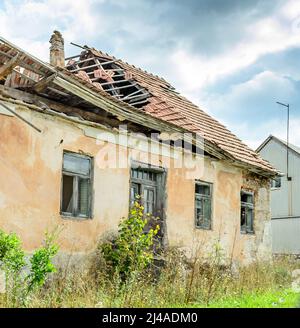 Ancienne maison démolie et détruite en Croatie. Cottage abandonné de l'époque de la guerre d'indépendance croate. Toit replié et fenêtres écrasées Banque D'Images