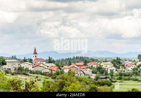 Paysage magnifique dans la campagne slovène. Village pittoresque avec des cottages traditionnels et une église avec beffroi dans un environnement naturel avec Tre Banque D'Images