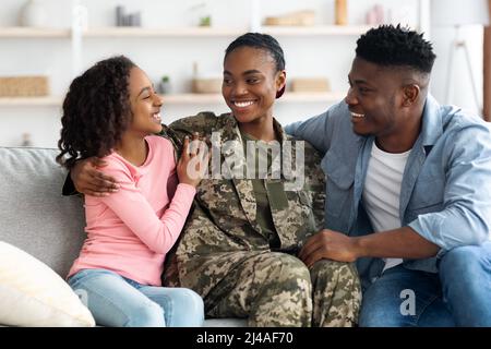 Famille afro-américaine aimante célébrant sa réunion avec sa mère soldat Banque D'Images