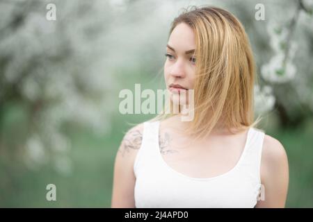 Fille blonde en robe blanche dans les jardins de printemps en fleur Banque D'Images
