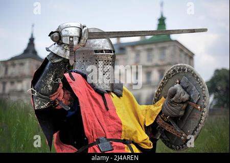 Chevalier médiéval avec épée et bouclier en armure sur le fond du château. Banque D'Images