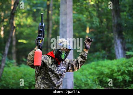 Le joueur de paintball est blessé et se rend avec ses mains levées Banque D'Images